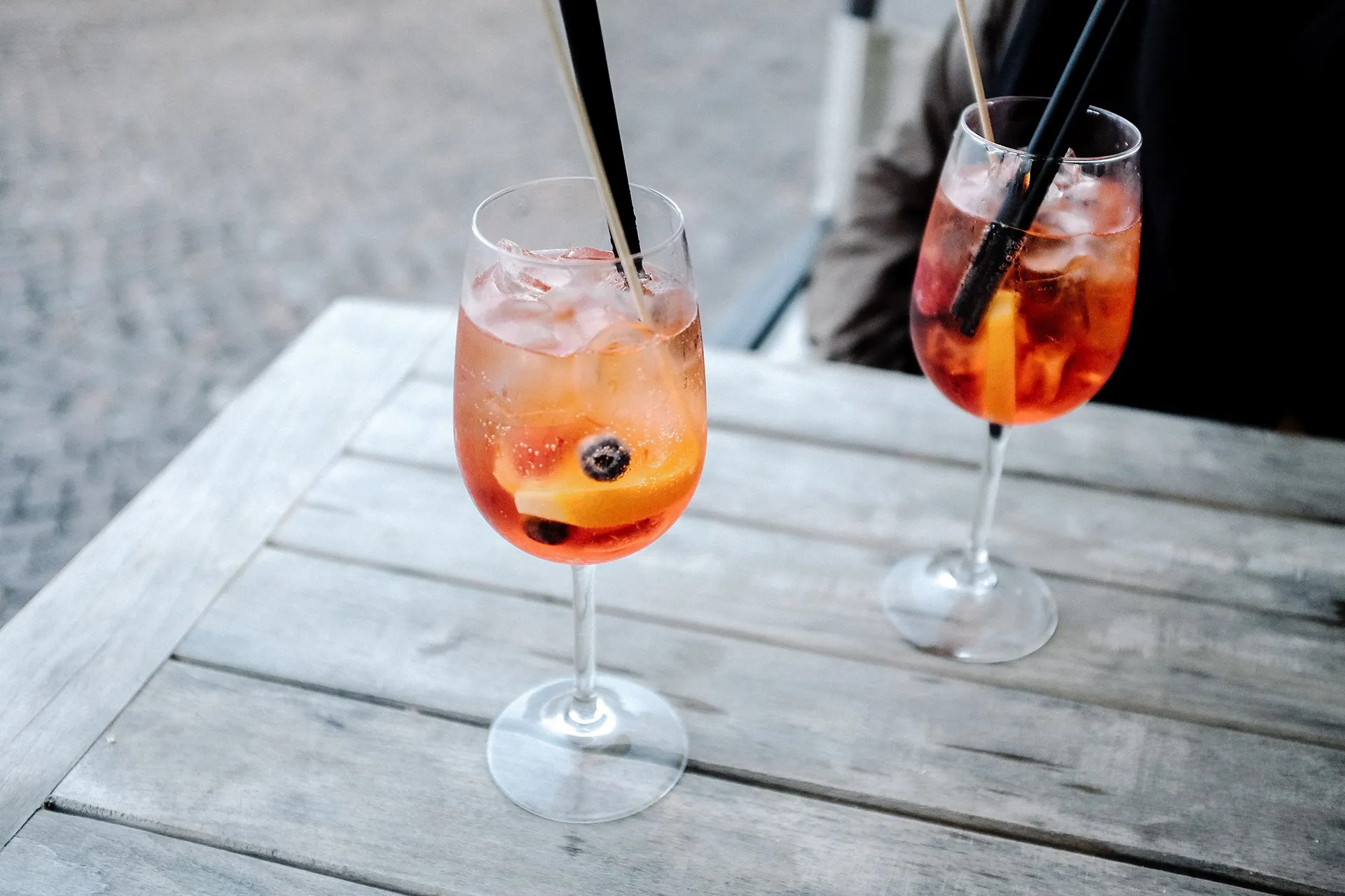 Two cocktails with straws on an outdoor wooden table